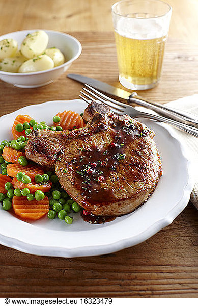 Pork chop with carrots  peas and boiled potatoes on plate