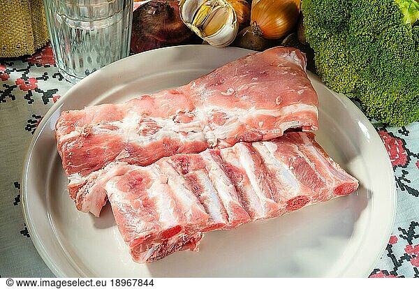 Pork ribs on a plate  rustic ambience around  with vegetable  glasses and bottle