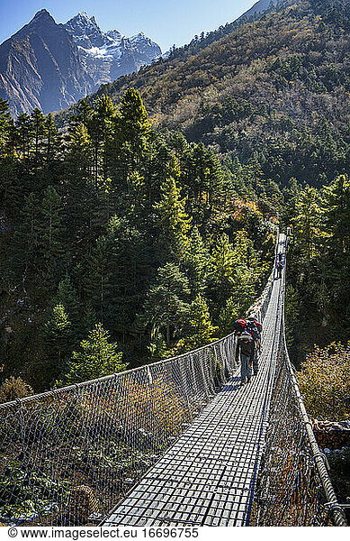 Porters carry gear across a bridge on the trail to Everest Base Camp.