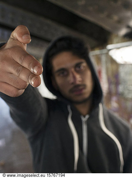 Porträt bedrohlicher junger Mann  der mit dem Finger eine Pistole zeigt