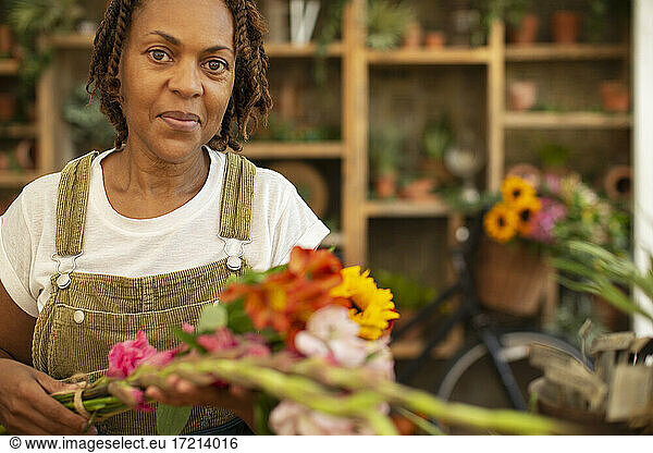Porträt Blumenhändlerin arrangiert Blumen im Geschäft
