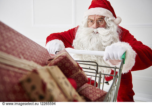 Porträt des Weihnachtsmannes mit Einkaufswagen von Weihnachtsgeschenken