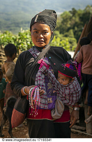 Porträt einer erwachsenen Frau vom Stamm der Eng  die ein Baby im Tuch trägt  in der Nähe von Kengtung  Myanmar