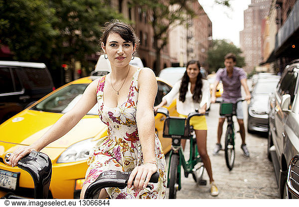 Porträt einer Fahrrad fahrenden Frau mit Freunden im Hintergrund