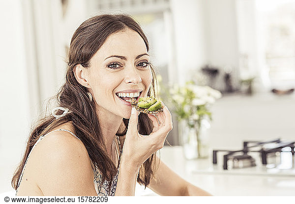 Porträt einer Frau  die ein gesundes Avocadobrot isst