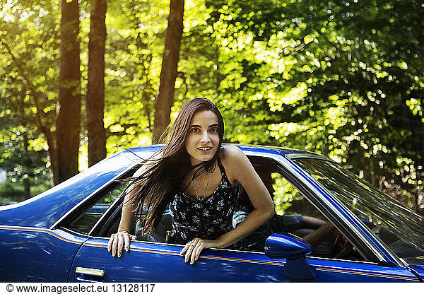 Porträt einer Frau  die sich im Wald aus dem Fenster eines Pick-up lehnt