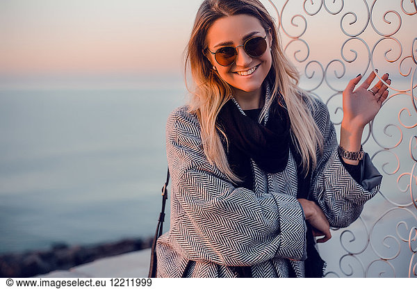 Porträt einer Frau mit Sonnenbrille und Wintermantel  die lächelnd in die Kamera schaut  Odessa  Odeska Oblast  Ukraine  Osteuropa
