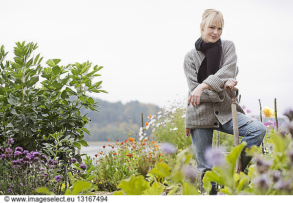 Porträt einer Frau mittleren Alters beim Graben im Bio-Garten