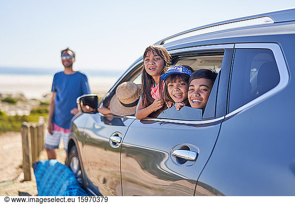 Porträt einer glücklichen Familie im Auto am sonnigen Strand