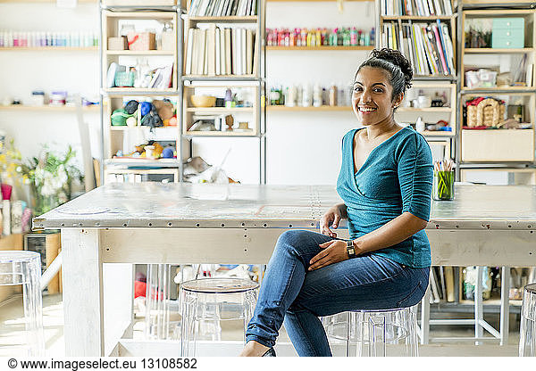 Porträt einer glücklichen Geschäftsfrau  die im Büro auf einem Hocker sitzt