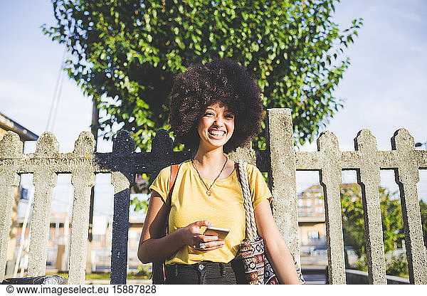 Porträt einer glücklichen jungen Frau mit Afrofrisur in der Stadt