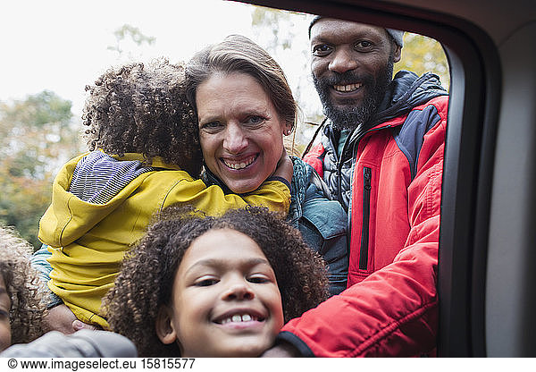 Porträt einer glücklichen multiethnischen Familie am Autofenster