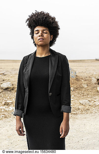 Porträt einer in Schwarz gekleideten jungen Frau in trostloser Landschaft stehend