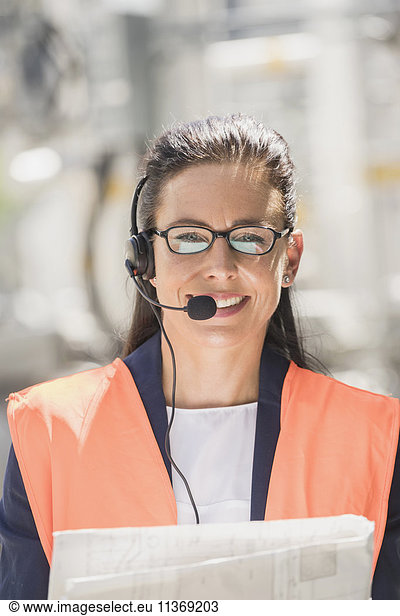 Porträt einer Ingenieurin mit Headset und Bauplan in einem geothermischen Kraftwerk