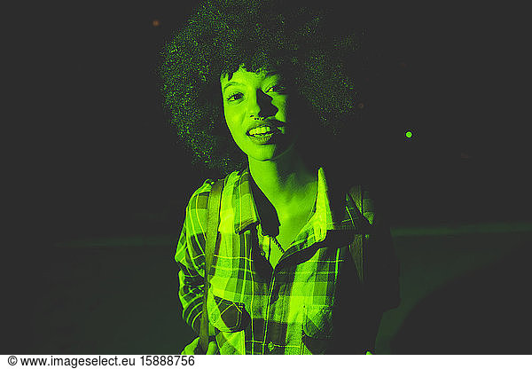 Porträt einer jungen Frau mit Afrofrisur im Freien bei Nacht