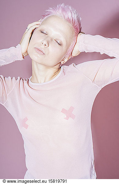 Porträt einer jungen Frau mit kurzen rosa Haaren  die ein rosa Top vor einem rosa Hintergrund trägt