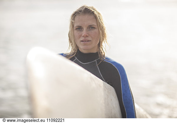 Porträt einer jungen Frau mit Surfbrett