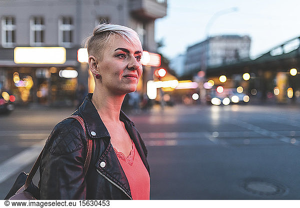 Porträt einer lächelnden blonden Frau am Straßenrand am Abend  Berlin  Deutschland