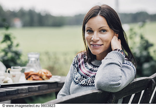 Porträt einer lächelnden Frau am Frühstückstisch im Bio-Bauernhof