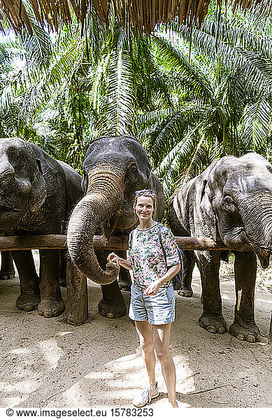 Porträt einer lächelnden Frau beim Füttern von Elefanten in einem Schutzgebiet  Krabi  Thailand
