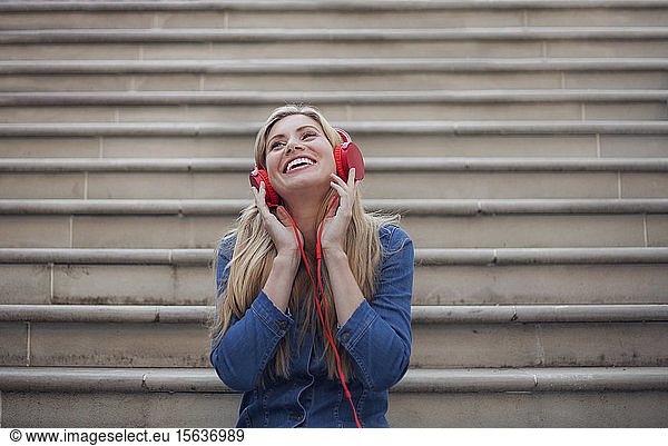 Porträt einer lächelnden Frau  die mit roten Kopfhörern Musik hört