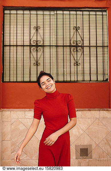 Porträt einer lächelnden Frau mit rotem Kleid vor einer roten Wand