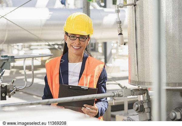 Porträt einer lächelnden Ingenieurin mit Dokument in einem geothermischen Kraftwerk