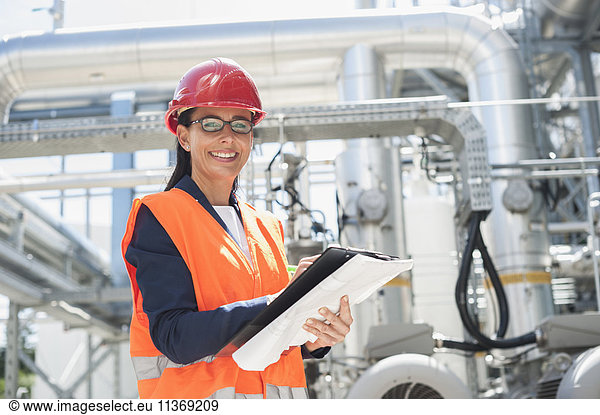 Porträt einer lächelnden Ingenieurin mit Dokument in einem geothermischen Kraftwerk