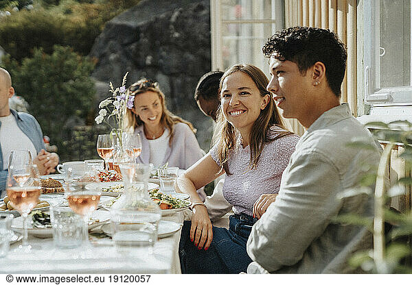 Porträt einer lächelnden jungen Frau  die mit Freunden bei einer Dinnerparty im Café sitzt