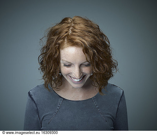 Porträt einer lächelnden rothaarigen Frau mit Blick nach unten