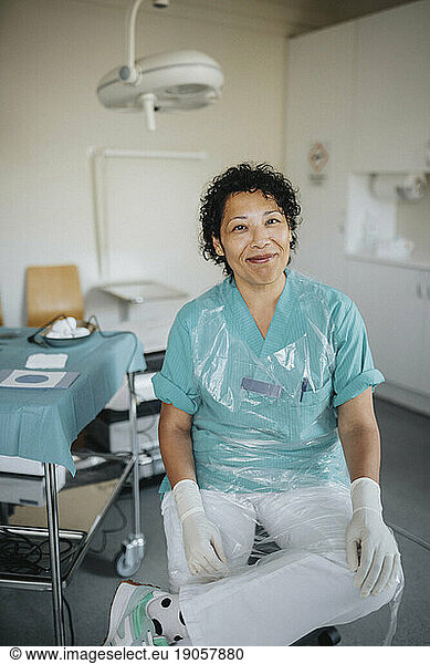 Porträt einer lächelnden Ärztin in Uniform  die in einem medizinischen Untersuchungsraum sitzt