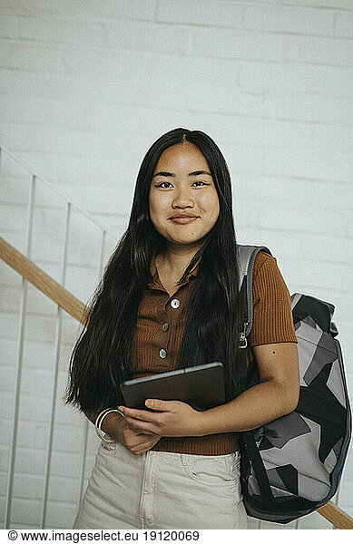 Porträt einer lächelnden Studentin mit Rucksack in der Universität