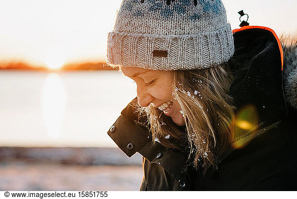 Porträt einer lachenden Frau  die im Winter draußen mit Schnee im Haar lacht