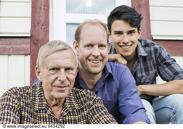 Porträt einer Mehrgenerationen-Familie  die vor dem Haus zusammensitzt