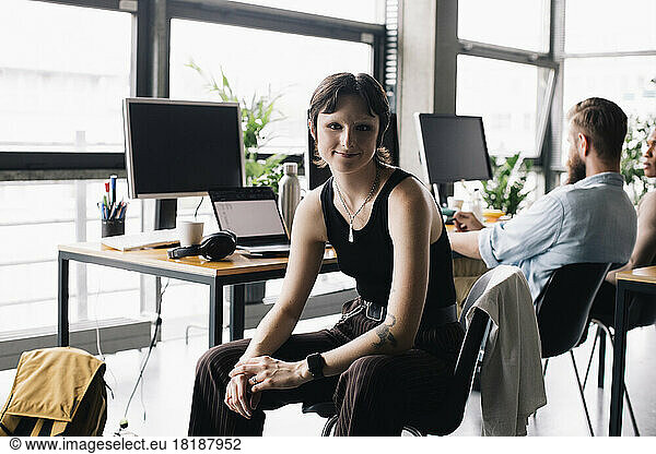 Porträt einer nicht-binären Geschäftsperson  die in einem neuen Büro auf einem Stuhl sitzt