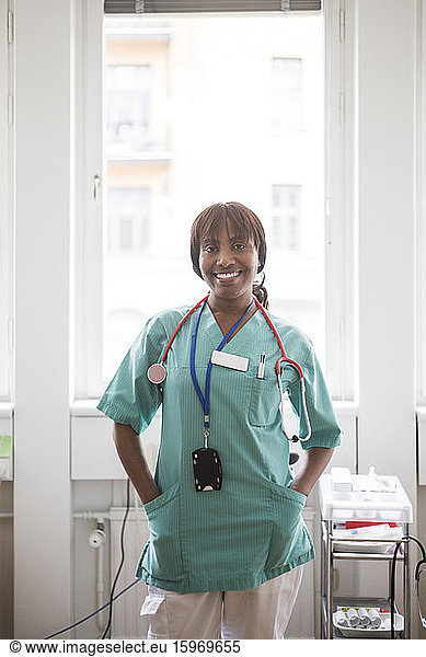 Porträt einer reifen Mitarbeiterin im Gesundheitswesen mit Händen in den Taschen stehend in der Klinik