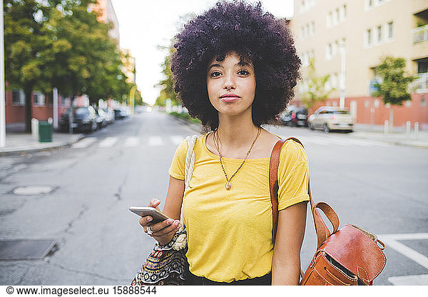 Porträt einer selbstbewussten jungen Frau mit Afrofrisur in der Stadt