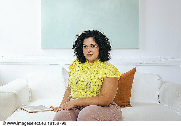 Porträt einer selbstbewussten jungen Geschäftsfrau  die mit einem digitalen Tablet sitzt