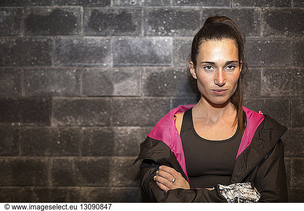 Porträt einer selbstbewussten Sportlerin  die die Arme gegen die Wand verschränkt