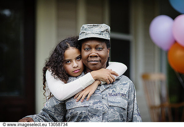 Porträt einer Tochter umarmt Soldat gegen Haus