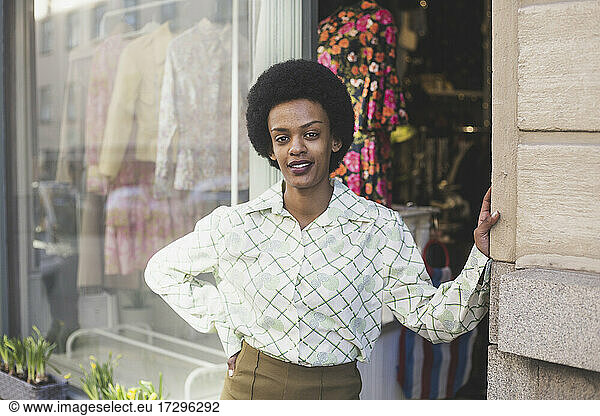 Porträt einer Unternehmerin mit Hand auf der Hüfte vor einer Boutique stehend