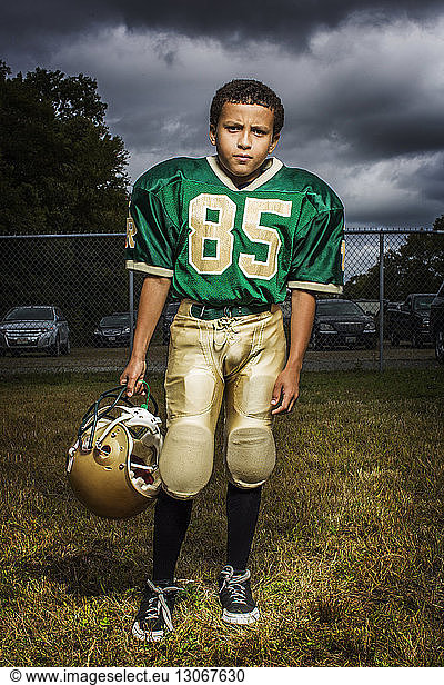 Porträt eines American-Football-Spielers auf dem Spielfeld vor bewölktem Himmel
