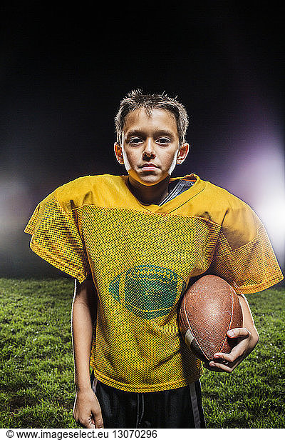 Porträt eines American-Football-Spielers mit auf dem Spielfeld stehendem Ball