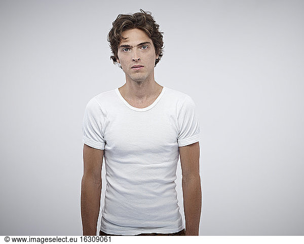 Porträt eines ernst dreinblickenden Mannes mit weißem T-Shirt vor weißem Hintergrund