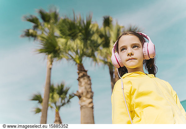 Porträt eines ernsten kleinen Mädchens  das im Freien mit Kopfhörern Musik hört