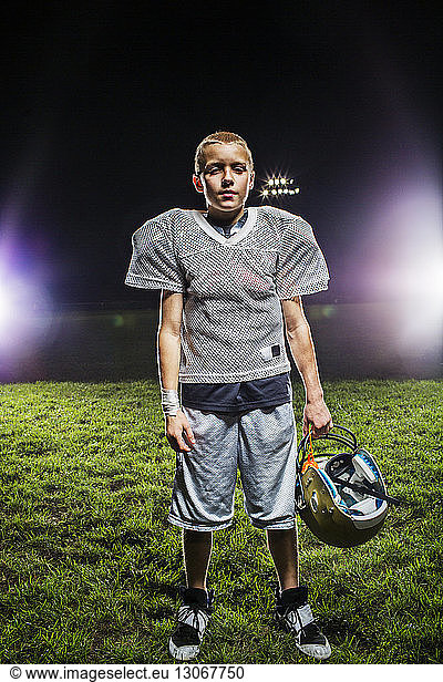 Porträt eines Fussballspielers  der einen Helm hält  während er auf dem Spielfeld steht