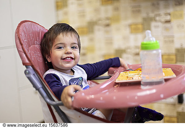 Porträt eines glücklichen kleinen Jungen auf einem Hochstuhl sitzend