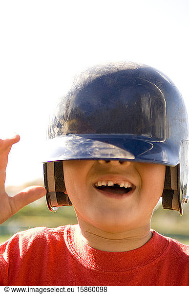 Porträt eines Jungen  dem ein Zahn fehlt  mit einem Baseballhelm  der über seinem Schneidebrett heruntergerissen wurde