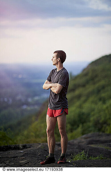 Porträt eines jungen erwachsenen Mannes  der auf einem Bergkamm läuft