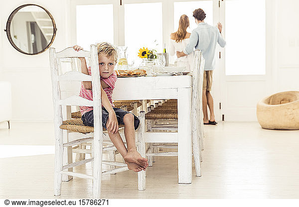 Porträt eines Jungen im Speisesaal mit den Eltern im Hintergrund
